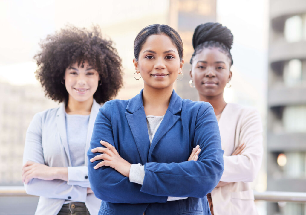 Three diverse businesswomen standing with arms folded and confident smiles