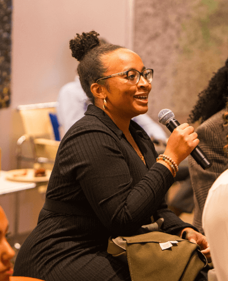 Black woman seated in audience with microphone to talk about tech