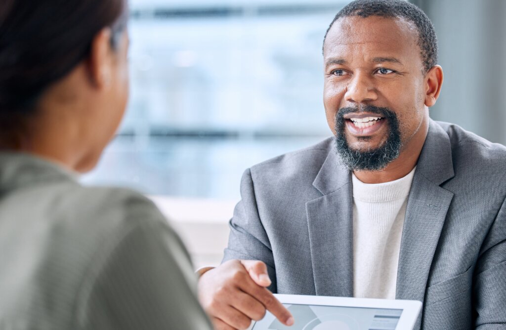 Black man showing data on a tablet to an employee or employer