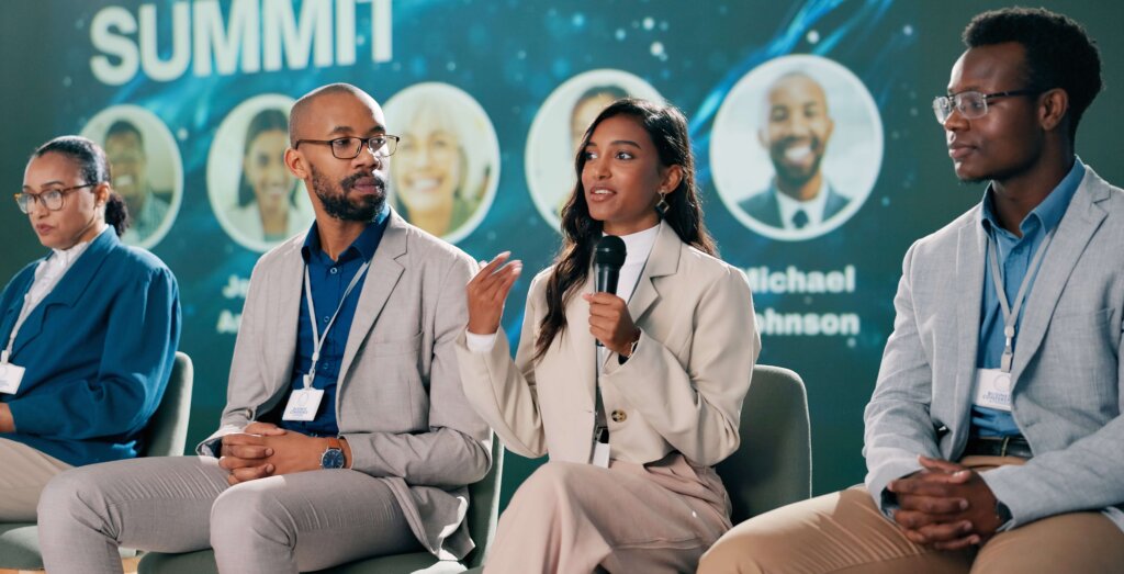 Diverse group speaking on stage with microphones at a Black tech conference