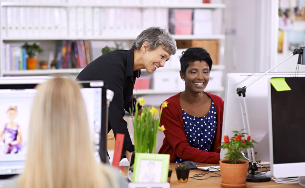 A businesswoman training another businesswoman on a computer.