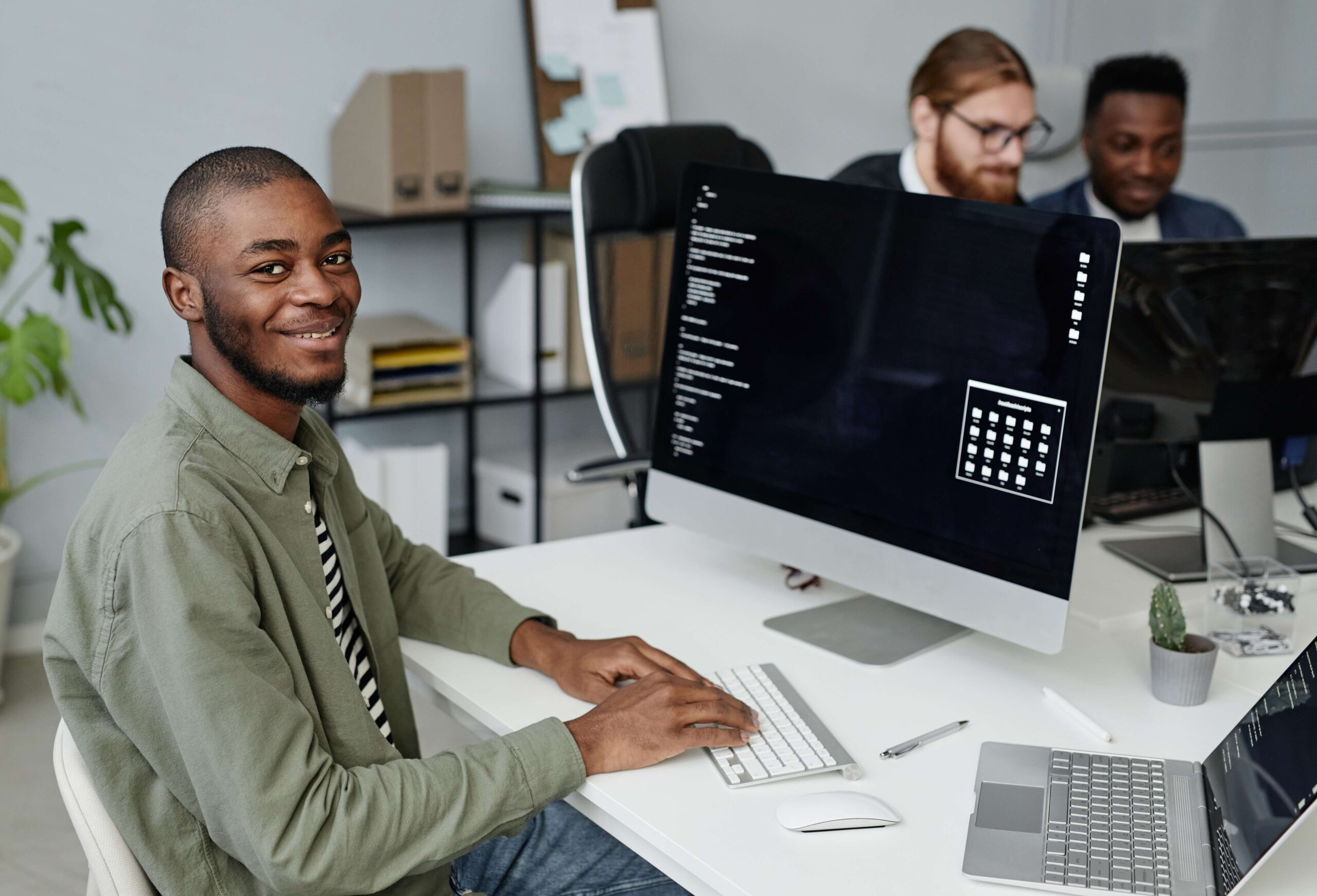 Black blockchain developer smiling at the camera from his workspace