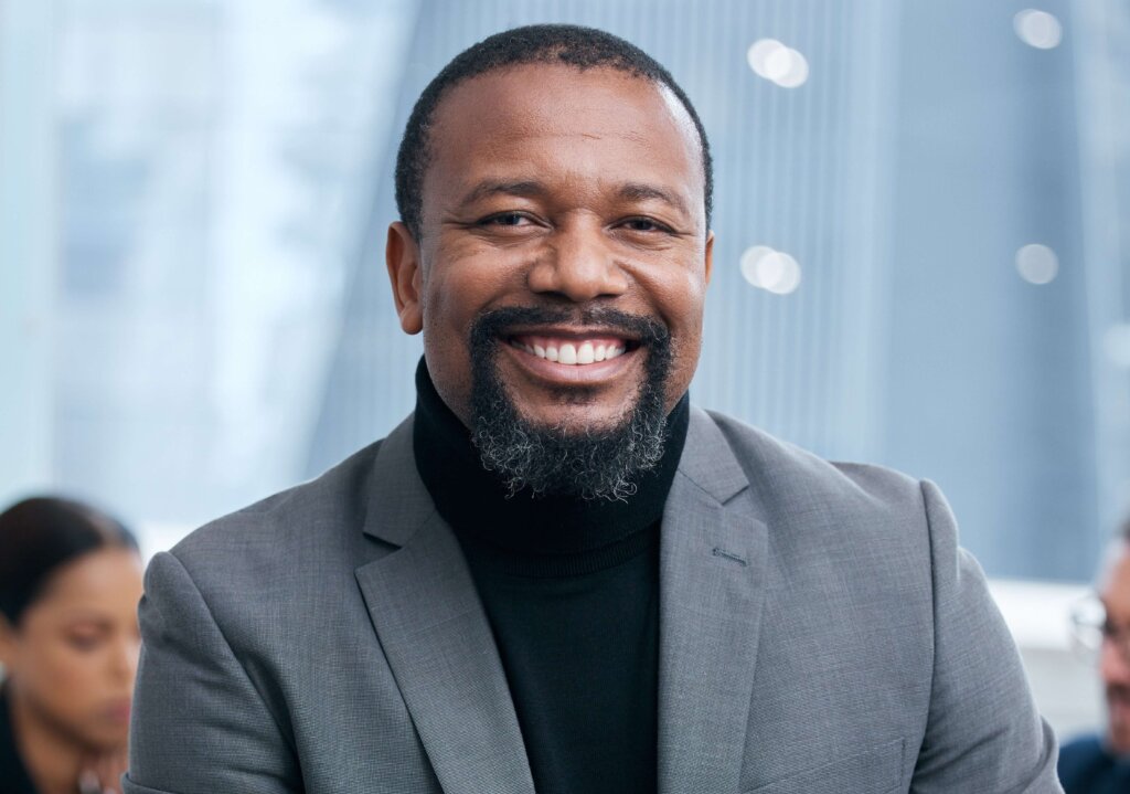 Black man with beard smiling happily to the camera
