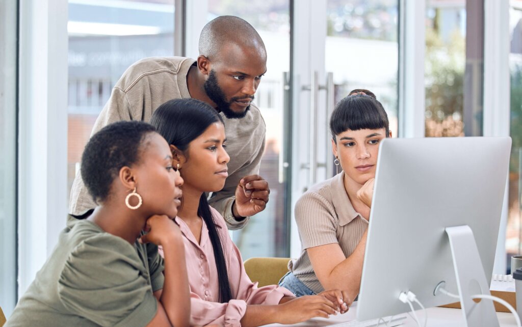 Diverse group of coworkers working on a project on a computer together